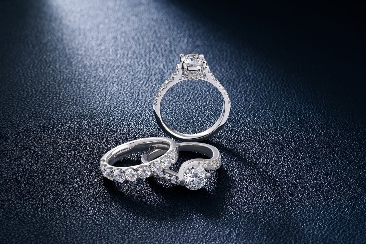 Services Close-up of luxurious diamond engagement and wedding rings on a textured surface, showcasing elegance and craftsmanship.