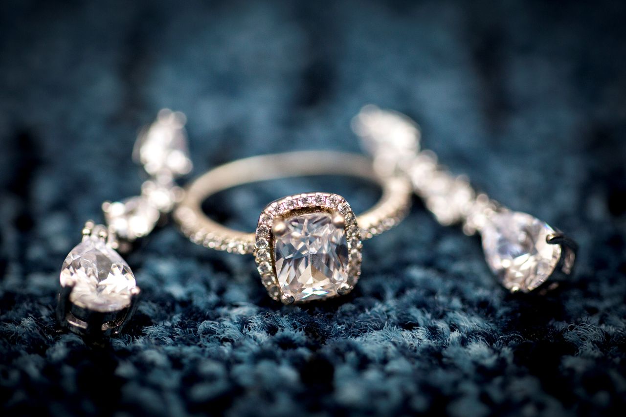 Services Stunning diamond ring displayed on a textured blue background, showcasing elegance and craftsmanship.