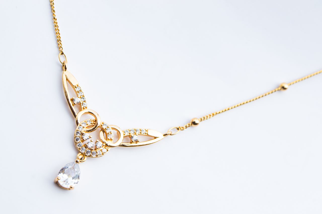 Services Luxury gold necklace featuring diamond accents on a white background.